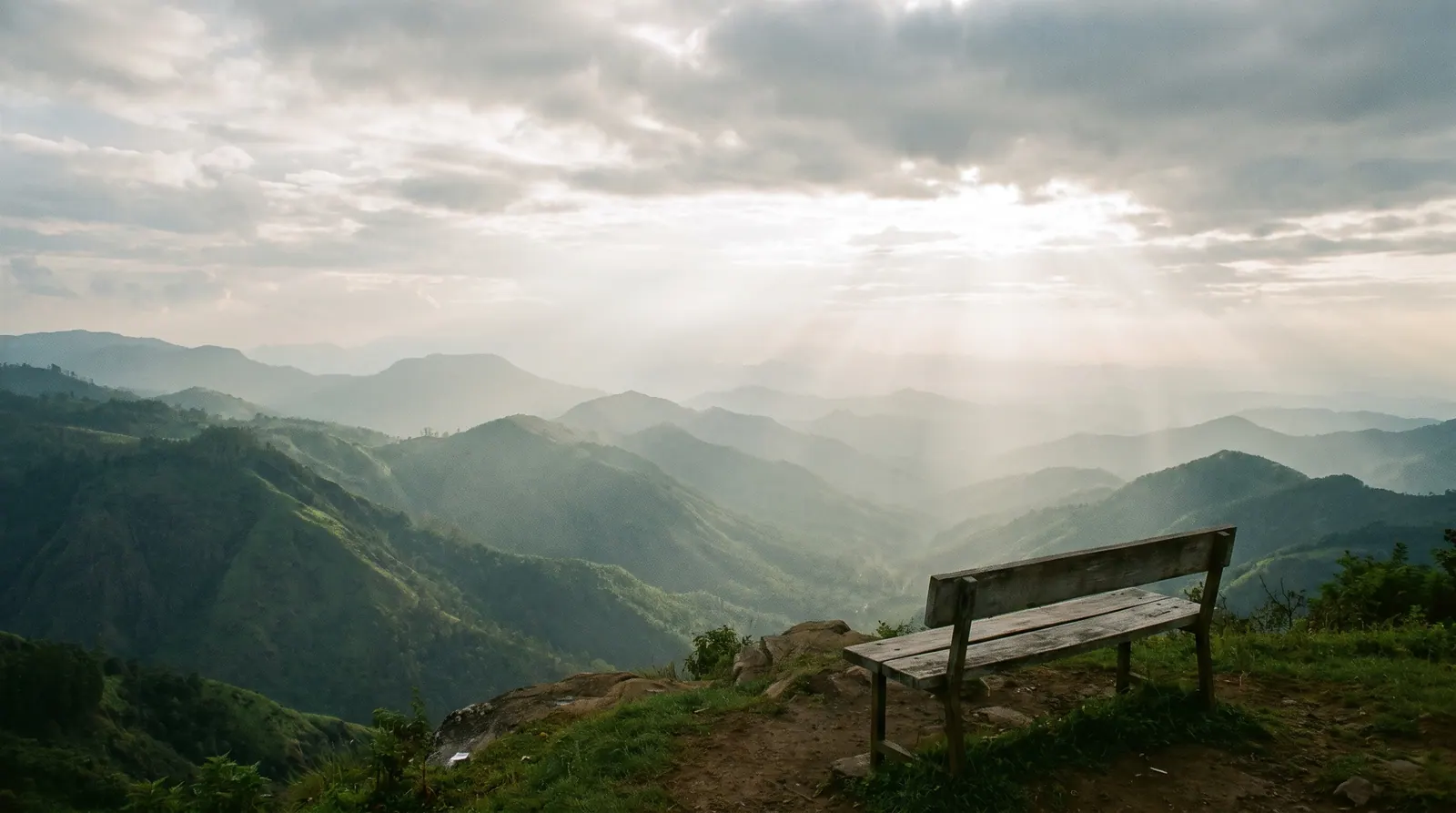 A lone bench at a green valley viewpoint with misty ridges in Kodaikanal