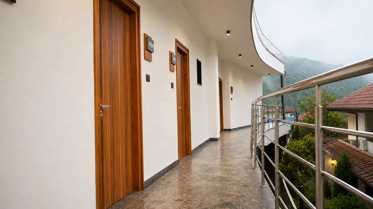A bright guest corridor with wood doors and a curved glass railing
