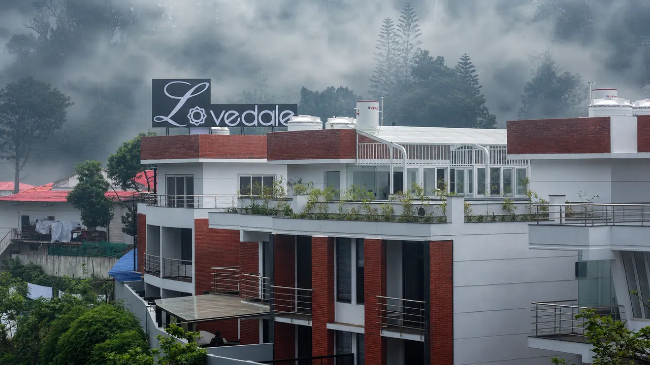 The Lovedale's façade and rooftop sign, red-tiled and white against the misty Kodaikanal town