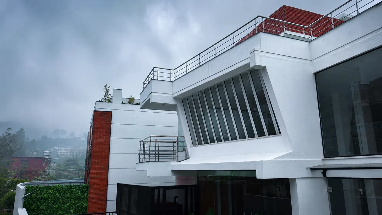 The hotel's white modern façade rising into thick Kodaikanal hill mist