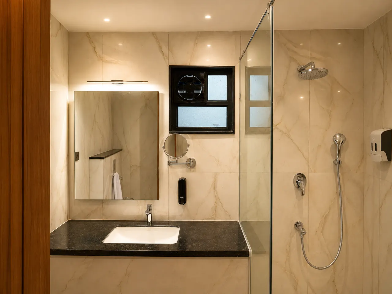 A room bathroom with a marble vanity, a large mirror and a glass-screened shower