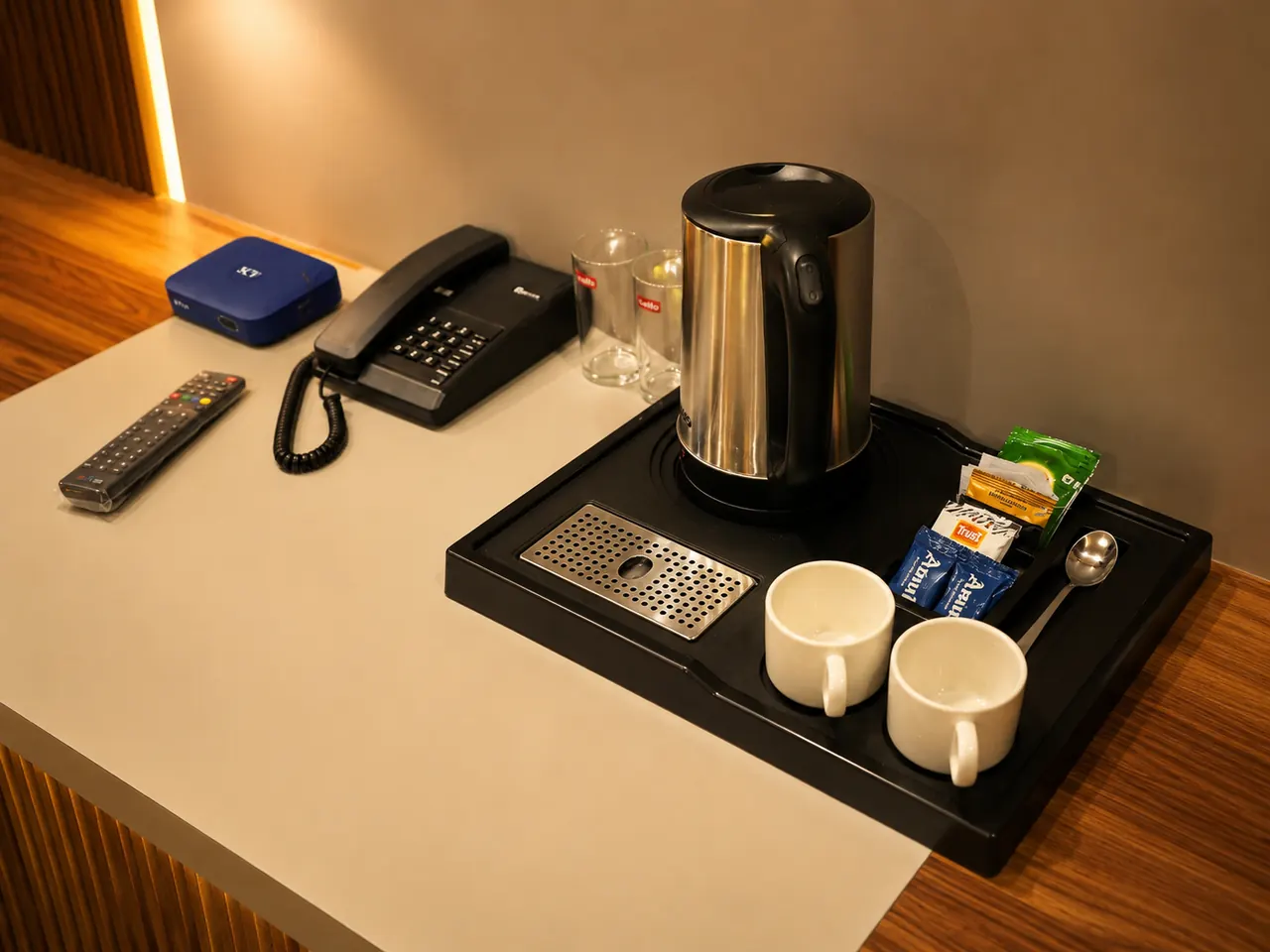 An in-room tea and coffee tray with an electric kettle, cups and a direct-dial phone