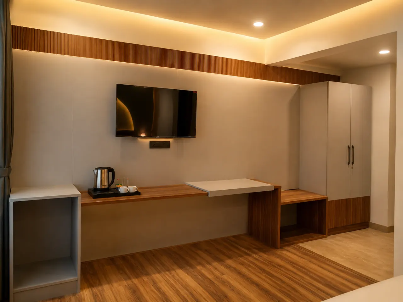 A room's work-and-storage corner, with a wall-mounted TV, desk and wardrobe in warm wood