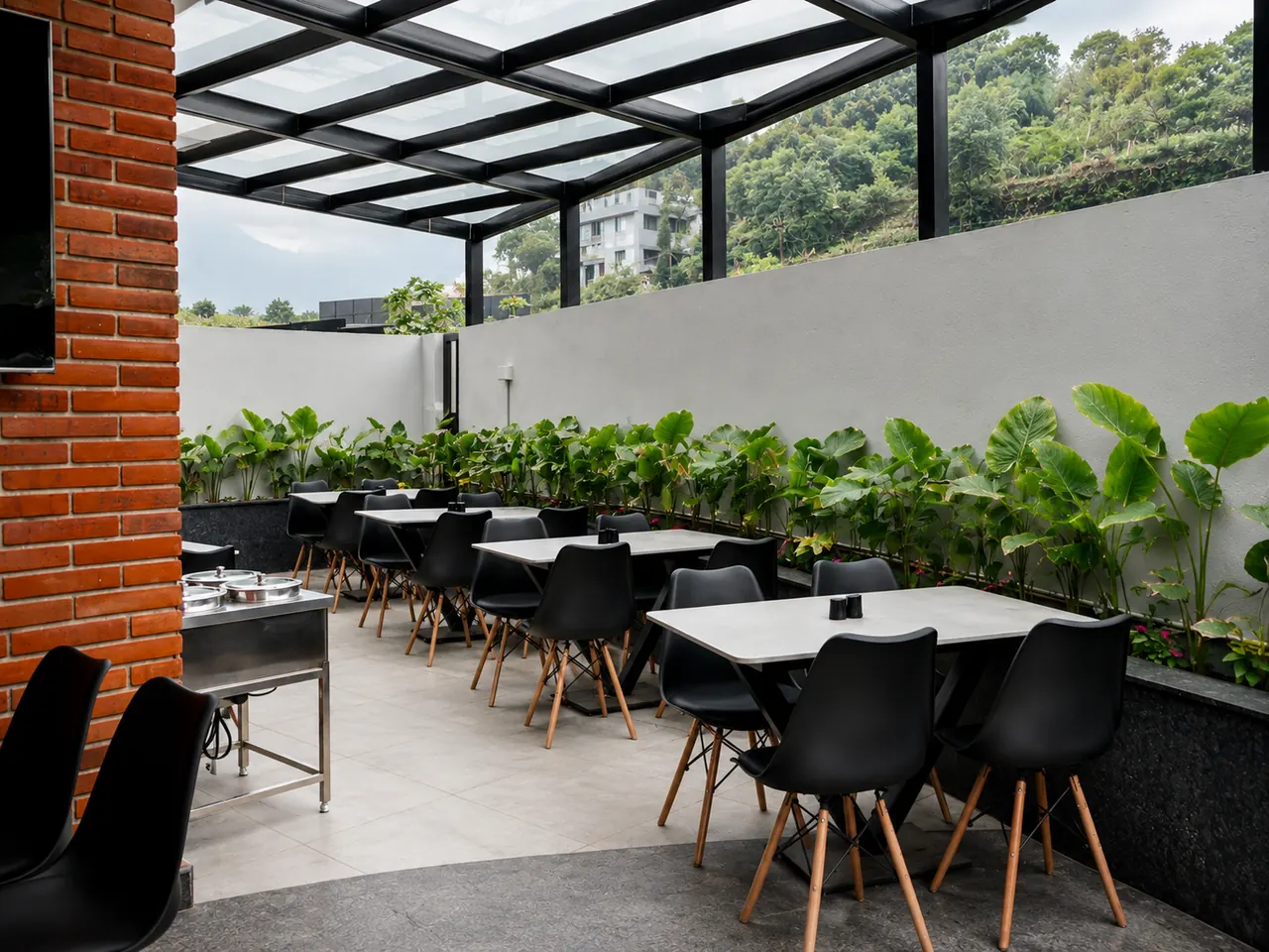 The glass-roofed terrace restaurant, ringed with plants and set for a meal